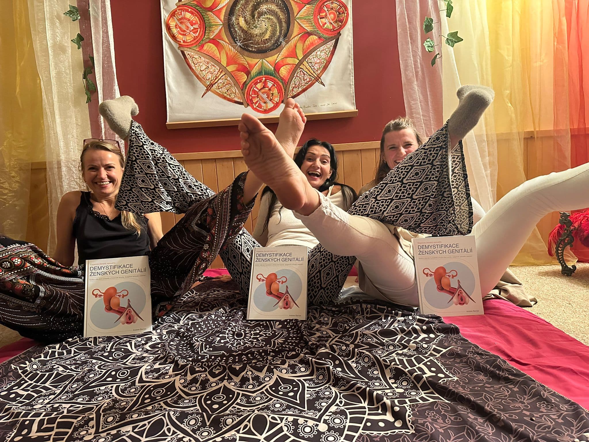 Three women laughing with copies of Demystifying Female Genitalia