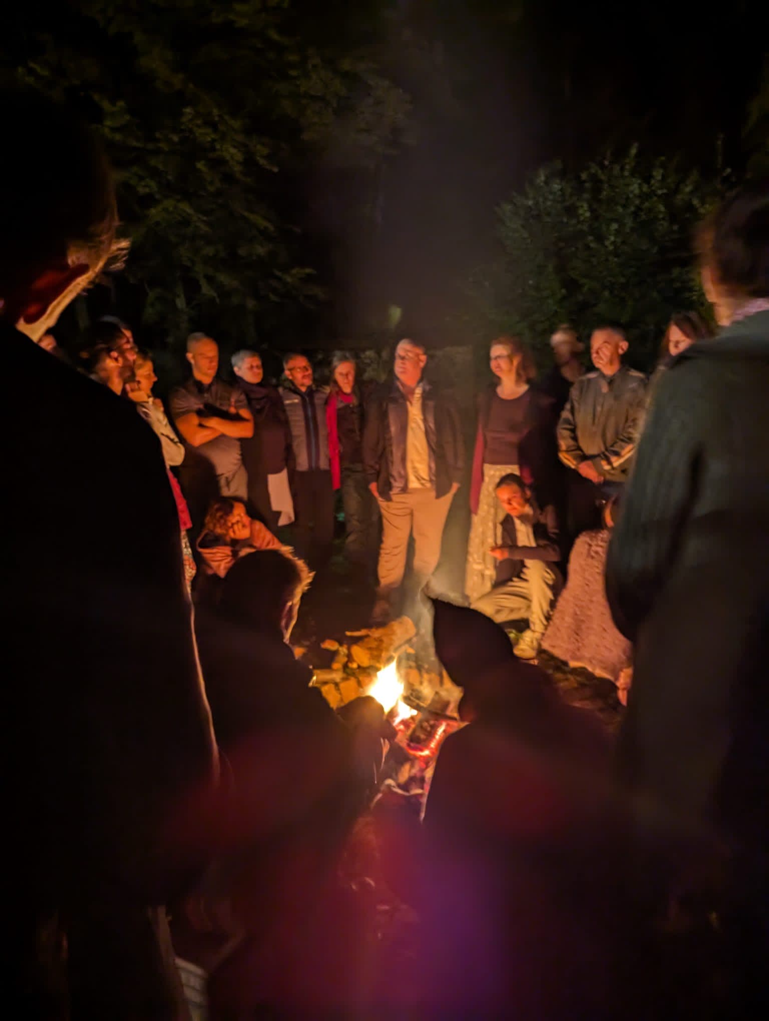 Andrew Barnes speaking with participants around a fire