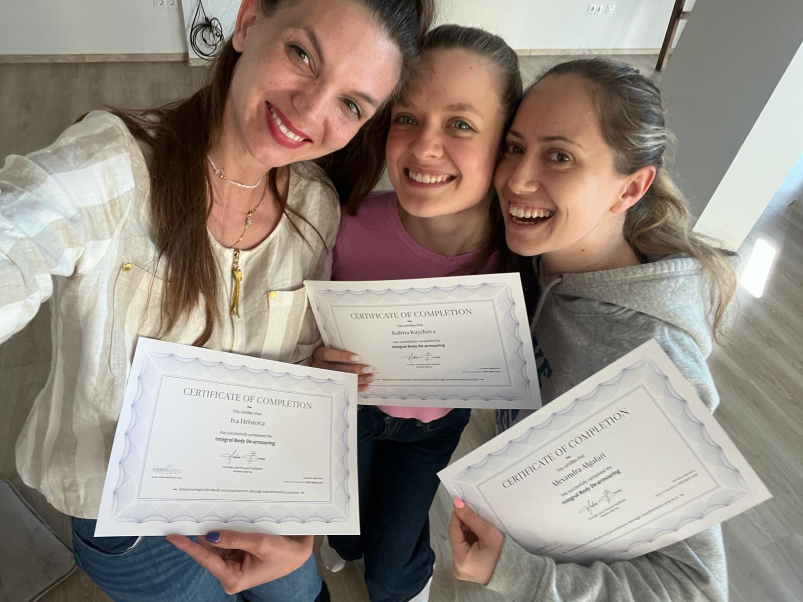 Three practitioners smiling and holding their certificates of completion